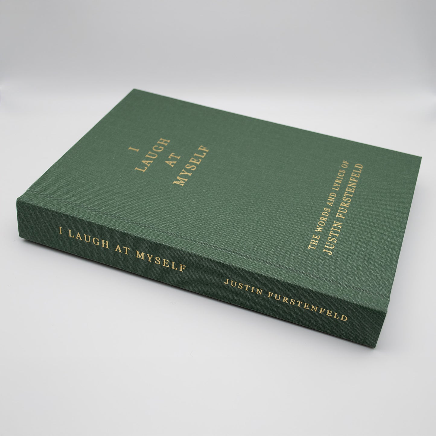 Green book titled 'I Laugh at Myself' by Justin Furstenfeld on a white background